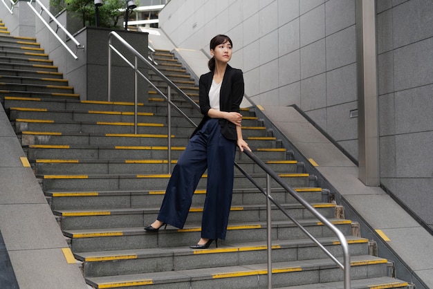 Tiro largo de hermosa mujer de negocios en escaleras