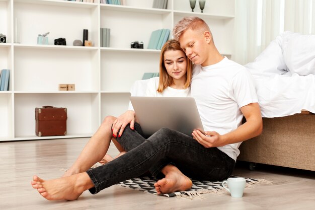Tiro largo hombre y mujer mirando una película en la computadora portátil