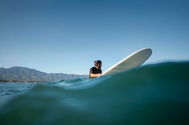 Tiro largo del hombre en su tabla de surf