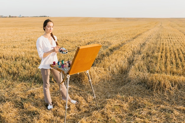 Foto gratuita tiro largo mujer pintura en la naturaleza