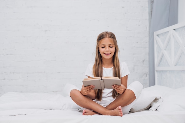 Tiro largo niña rubia leyendo un libro