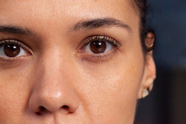 Tiro macro del primer de la cara hermosa de la persona del sexo femenino. Mujer con look natural limpio sin maquillaje. Adulto relajado con hermosos ojos marrones brillantes mirando a la cámara. Visión de glamour de cosméticos