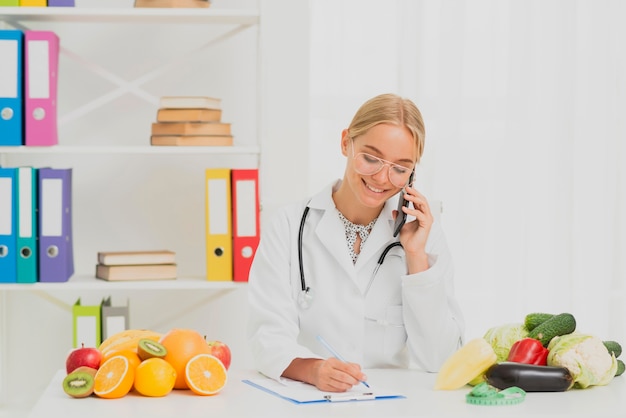 Foto gratuita tiro mediano nutricionista sonriente hablando por teléfono