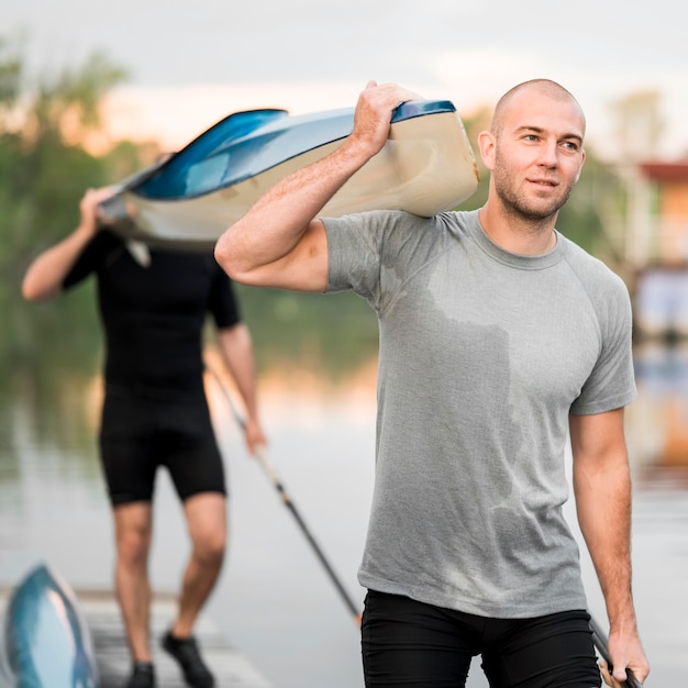 Foto gratuita tiro medio amigos llevando una canoa