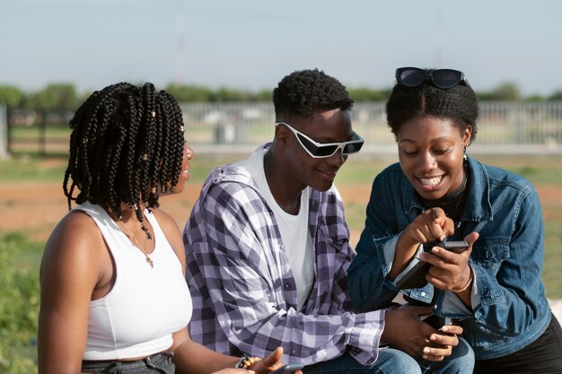 Tiro medio amigos mirando el teléfono inteligente