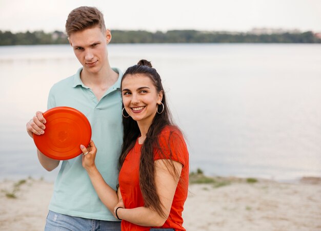 Tiro medio amigos sonrientes con frisbee rojo