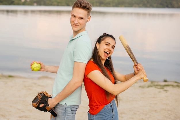 Tiro medio amigos sonrientes posando con equipo de béisbol