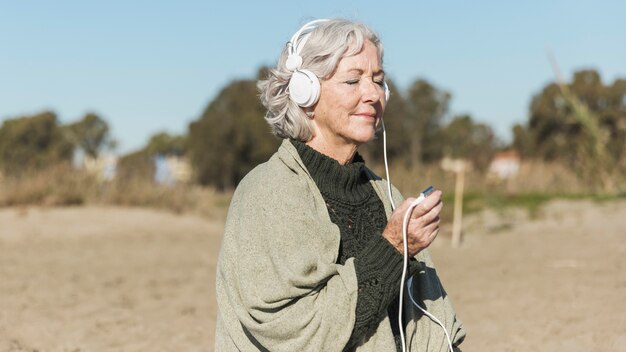 Tiro medio anciana escuchando música