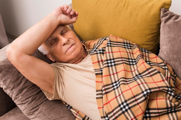 Tiro medio anciano enfermo tendido en el sofá