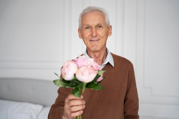 Foto gratuita tiro medio anciano sosteniendo flores