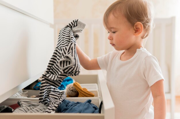 Tiro medio bebé sacando ropa del cajón