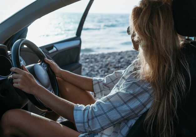 Tiro medio chica sentada en el asiento del conductor cerca del mar