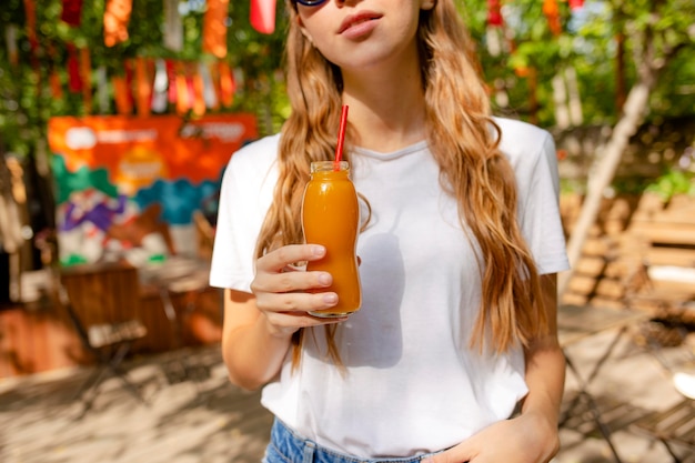 Tiro medio chica sosteniendo una botella de jugo fresco en el parque