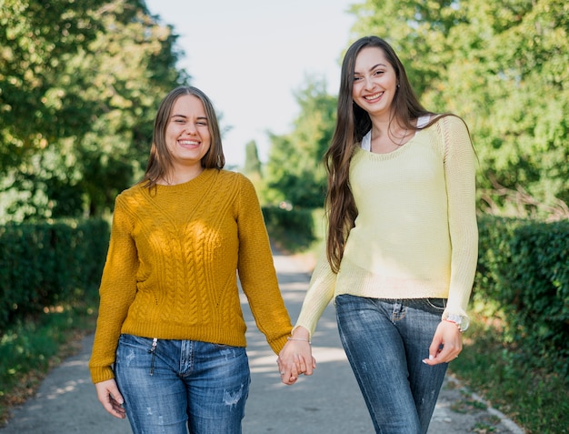 Tiro medio chicas sonrientes cogidos de la mano