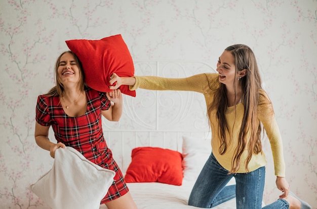 Foto gratuita tiro medio chicas sonrientes en una pelea de almohadas