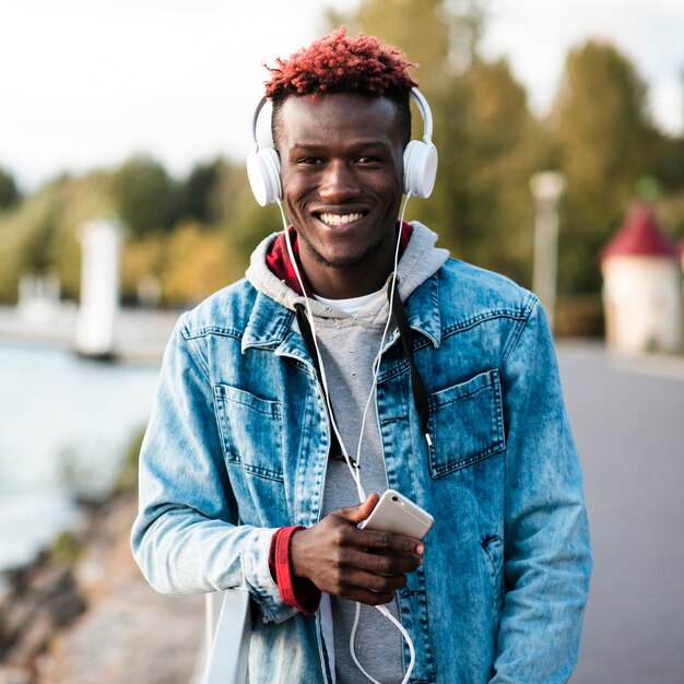 Tiro medio chico feliz sosteniendo su teléfono inteligente