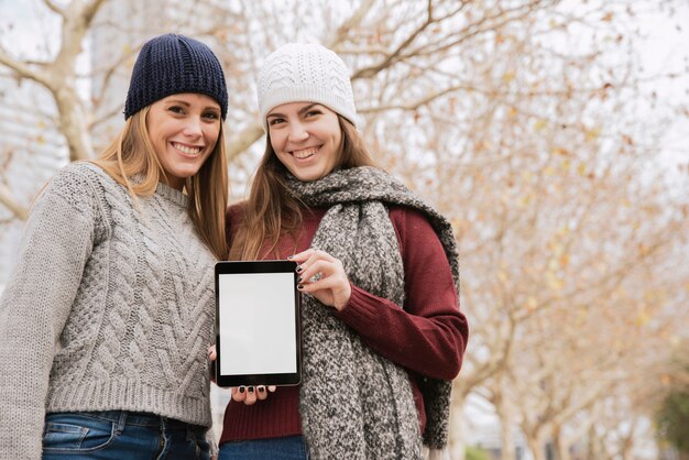 Tiro medio dos mujeres elegantes con tableta en manos