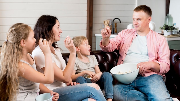 Tiro medio, familia comiendo palomitas de maíz