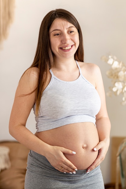 Foto gratuita tiro medio feliz mujer embarazada en interiores