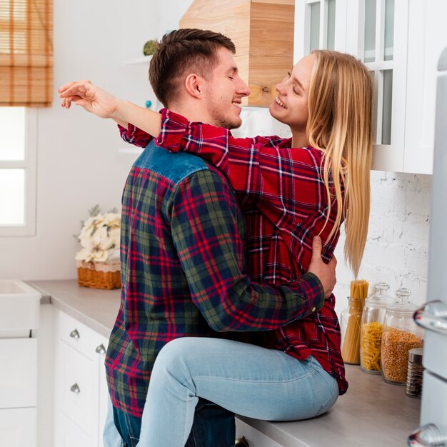 Tiro medio feliz mujer sentada en la encimera de la cocina