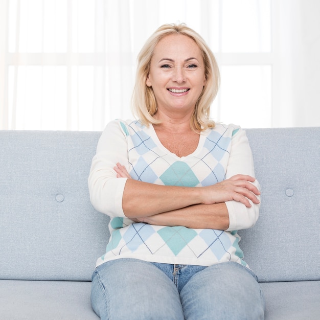 Tiro medio feliz mujer sentada en el sofá