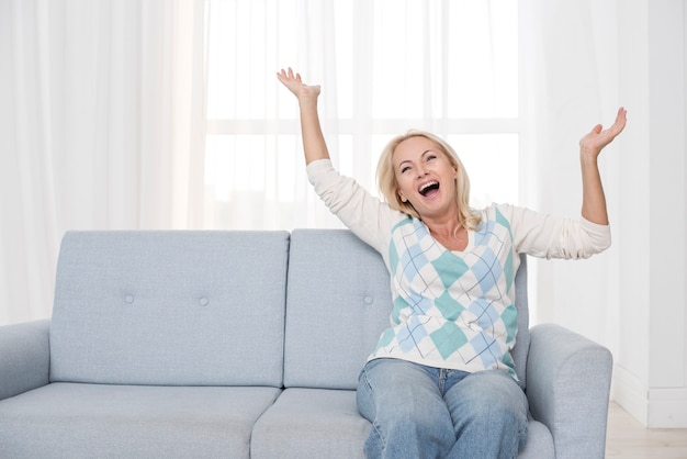 Foto gratuita tiro medio feliz mujer sentada en el sofá