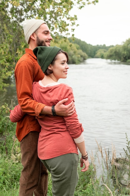 Tiro medio feliz pareja mirando hacia el agua