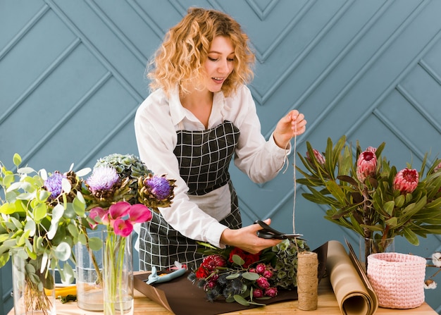 Foto gratuita tiro medio florista corte hilo para ramo