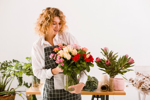 Tiro medio florista sonriente sosteniendo tarro con flores