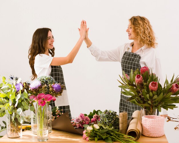 Tiro medio floristas choca los cinco en interiores