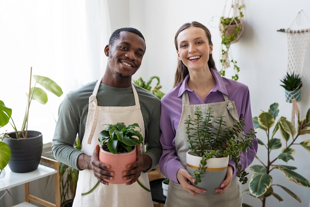 Tiro medio gente feliz con plantas.