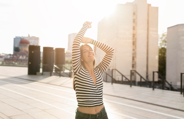 Tiro medio hermosa mujer sonriente posando en la luz del sol