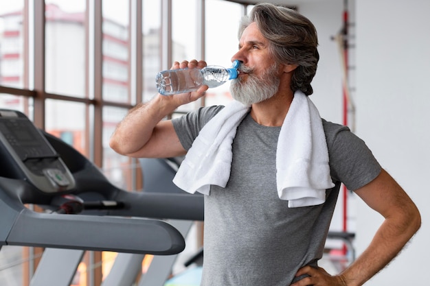 Tiro medio hombre agua potable en el gimnasio