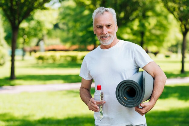 Tiro medio hombre con botella de agua y colchoneta