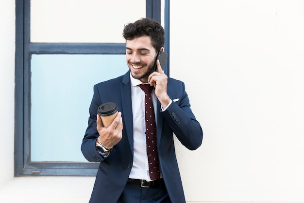 Tiro medio hombre con café hablando por teléfono