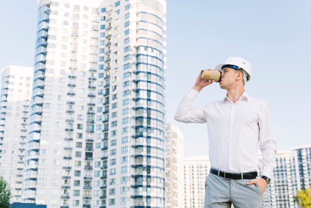 Foto gratuita tiro medio hombre con casco tomando café