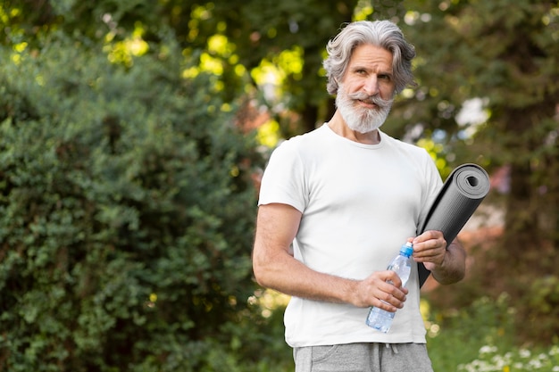 Tiro medio hombre con colchoneta de yoga y agua