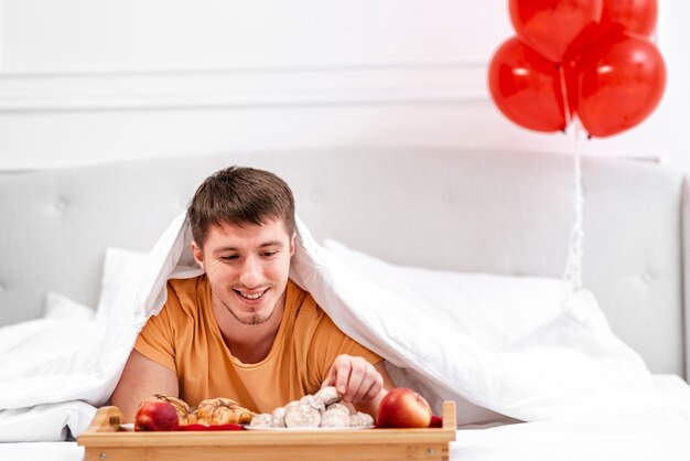 Tiro medio hombre con desayuno en la cama