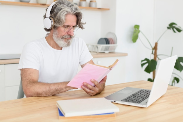 Tiro medio hombre en el escritorio mirando el libro