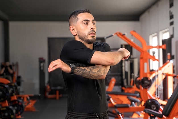 Foto gratuita tiro medio hombre estirando en el gimnasio