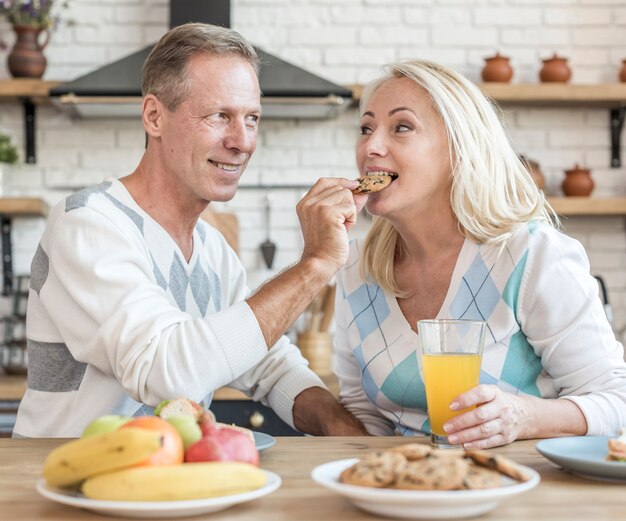 Tiro medio hombre feliz alimentación mujer