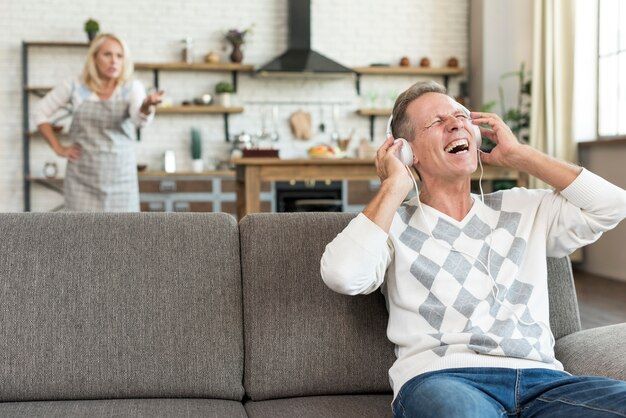 Tiro medio hombre feliz con auriculares en el sofá