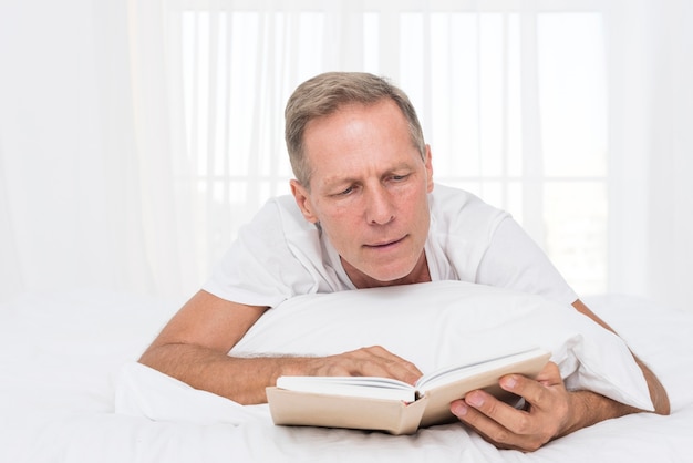 Foto gratuita tiro medio hombre leyendo en el dormitorio