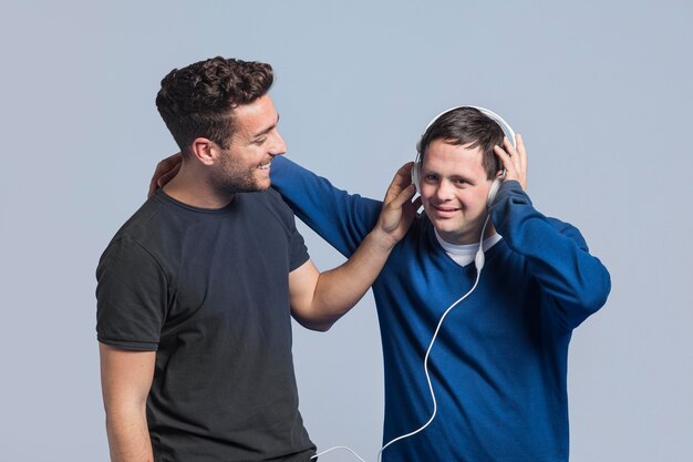 Tiro medio hombre mostrando a su amigo una canción a través de auriculares