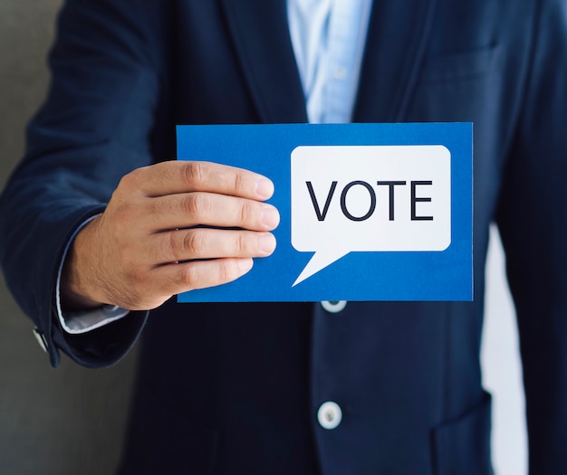 Tiro medio hombre mostrando una tarjeta de votación con un bocadillo