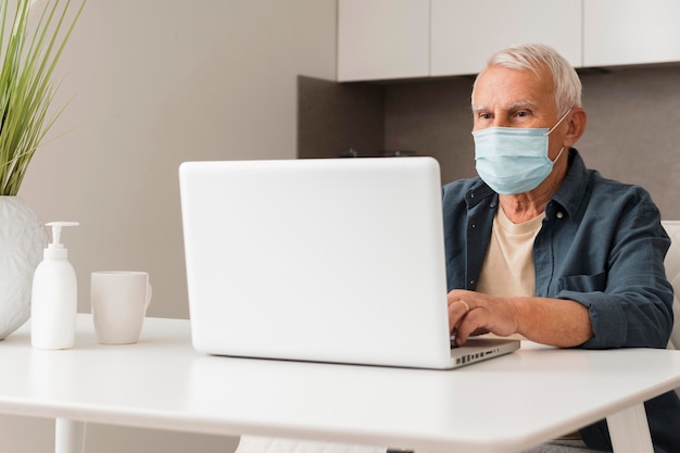 Foto gratuita tiro medio hombre sentado en un escritorio con máscara