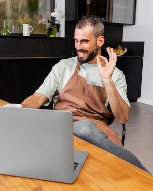 Foto gratuita tiro medio hombre sentado a la mesa con delantal