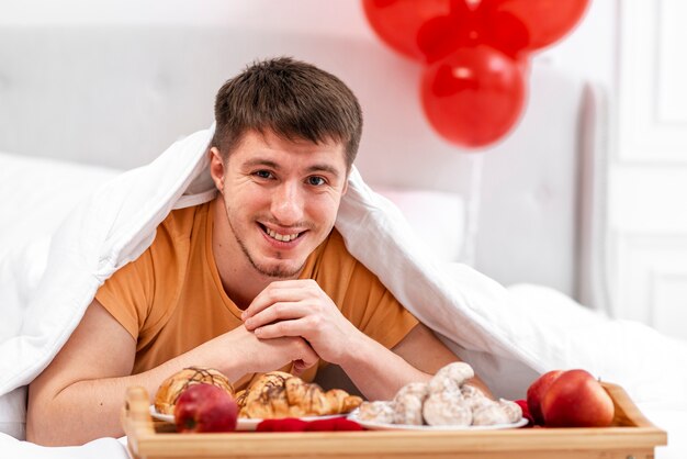 Foto gratuita tiro medio hombre sonriente con desayuno en la cama