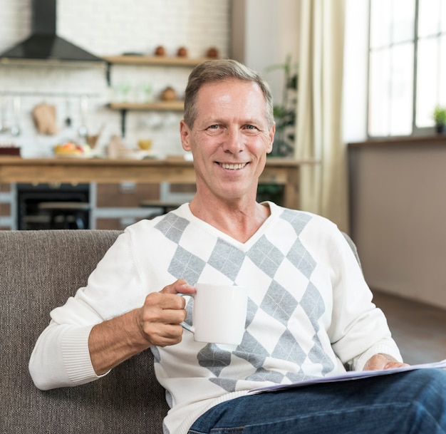 Tiro medio hombre sonriente leyendo con taza