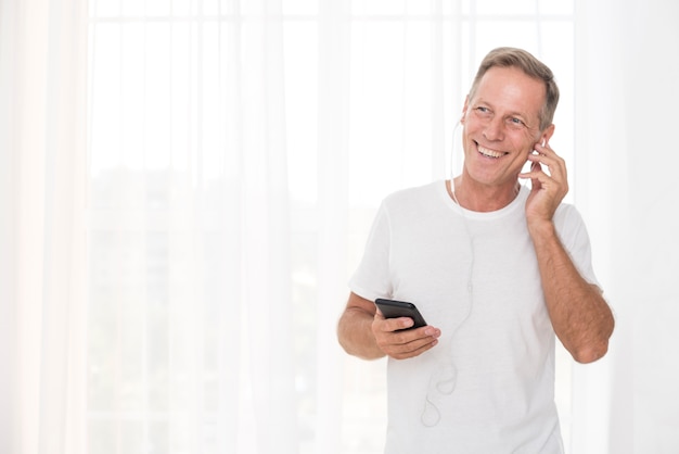 Tiro medio hombre sonriente con teléfono inteligente y auriculares